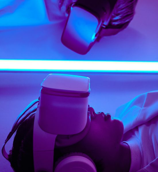 Close-up of a person using a VR headset under neon lights, reflecting futuristic themes.